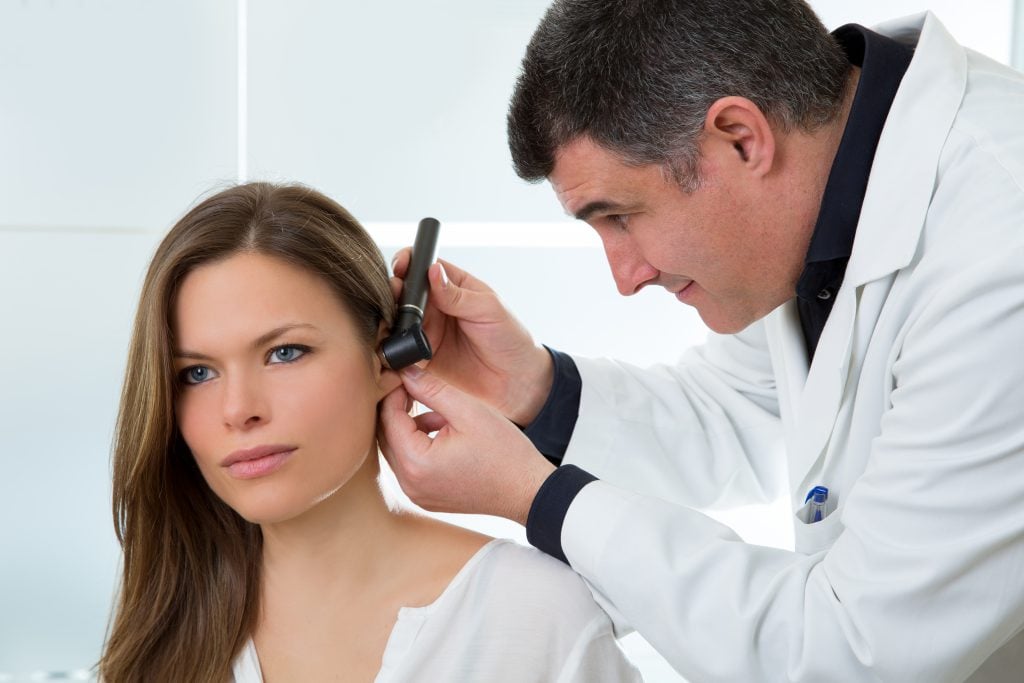 doctor ent checking ear with otoscope woman patient